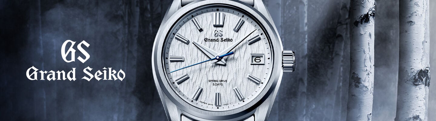 Grand Seiko silver stainless steel watch with white dial and metal bracelet on a dark blue background